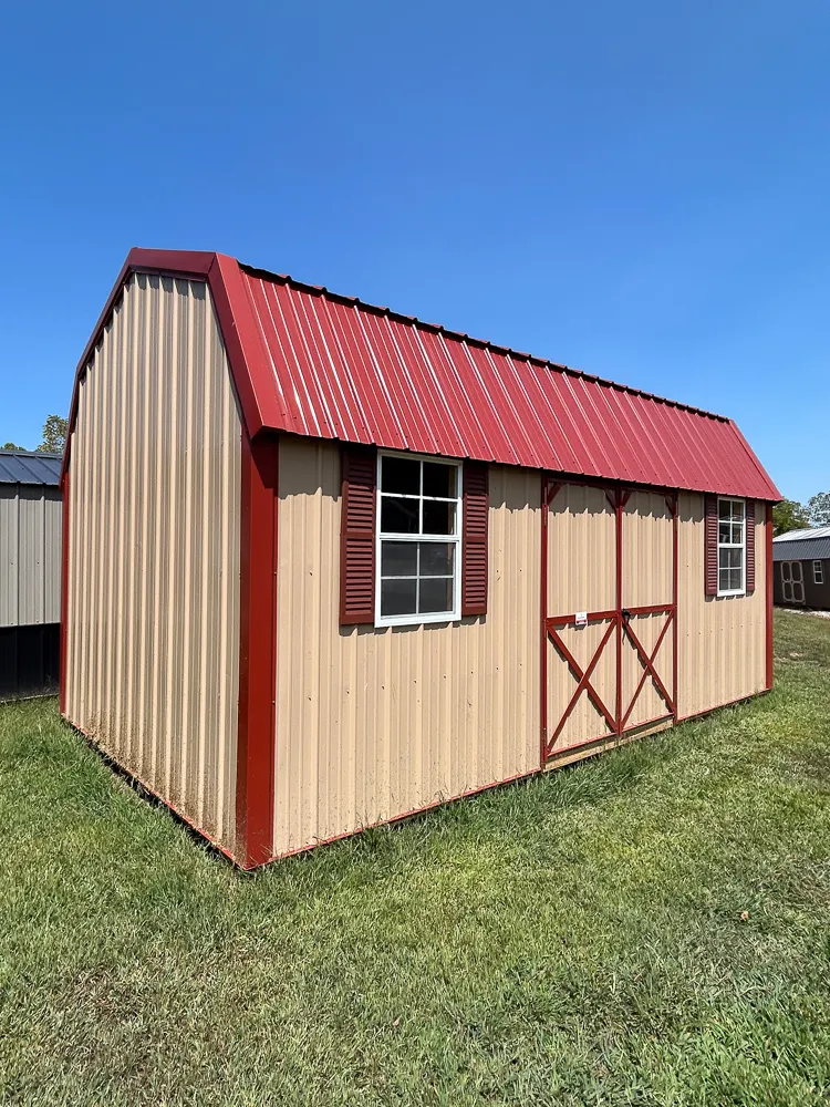 Tan lofted shed with a red metal roof and red trim
