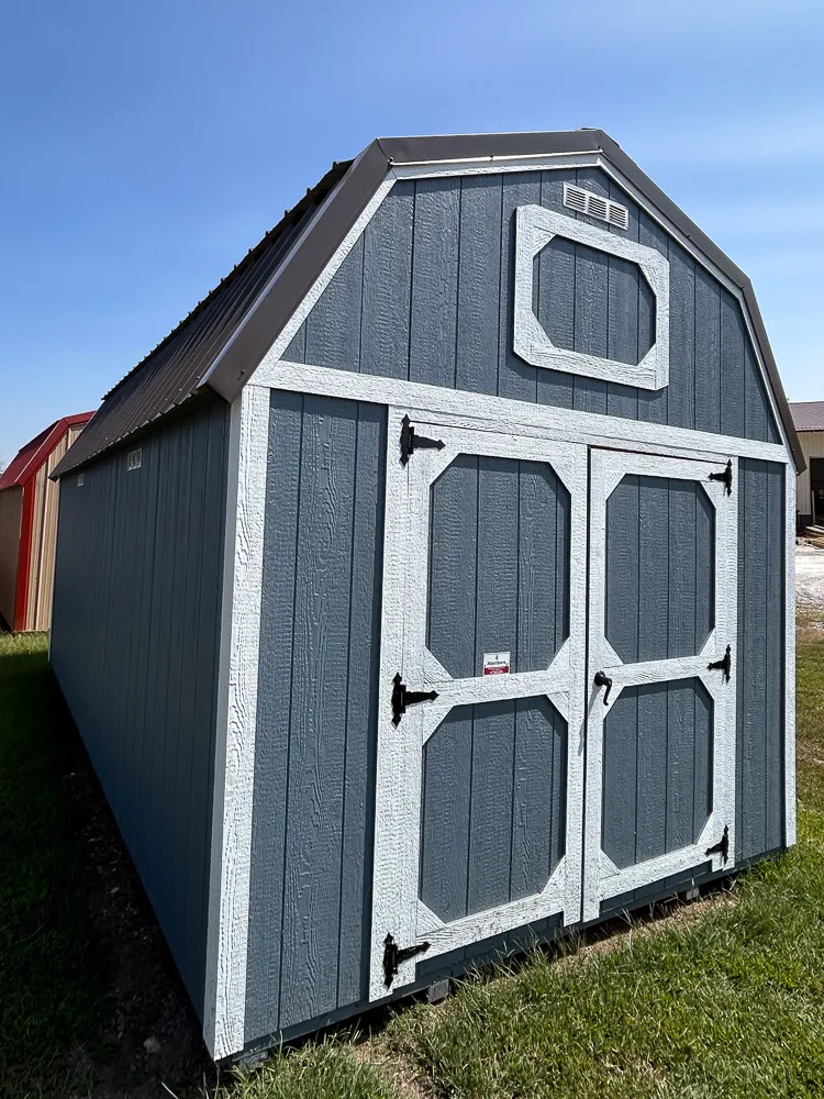 Gray gambrel barn shed with white octagon-braced double doors