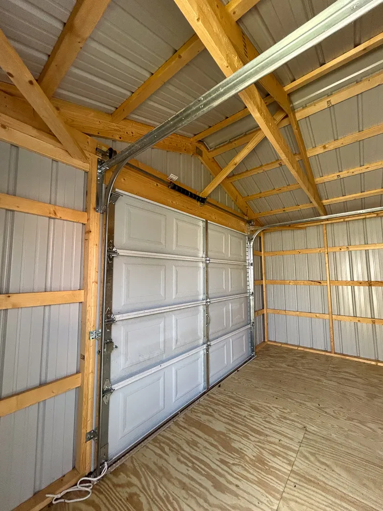 Inside a portable garage, looking up at the roof framing and garage door
