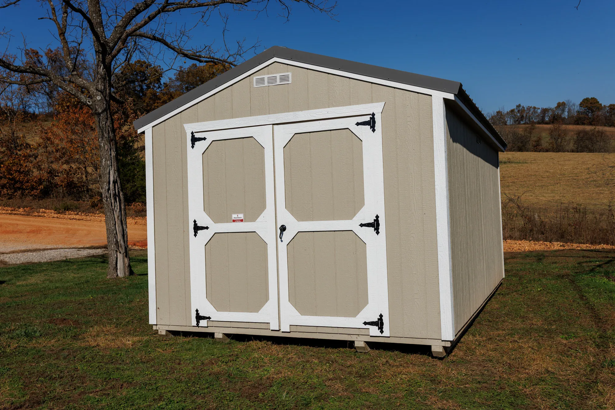 Tan Amish-built utility shed with white-trimmed double doors