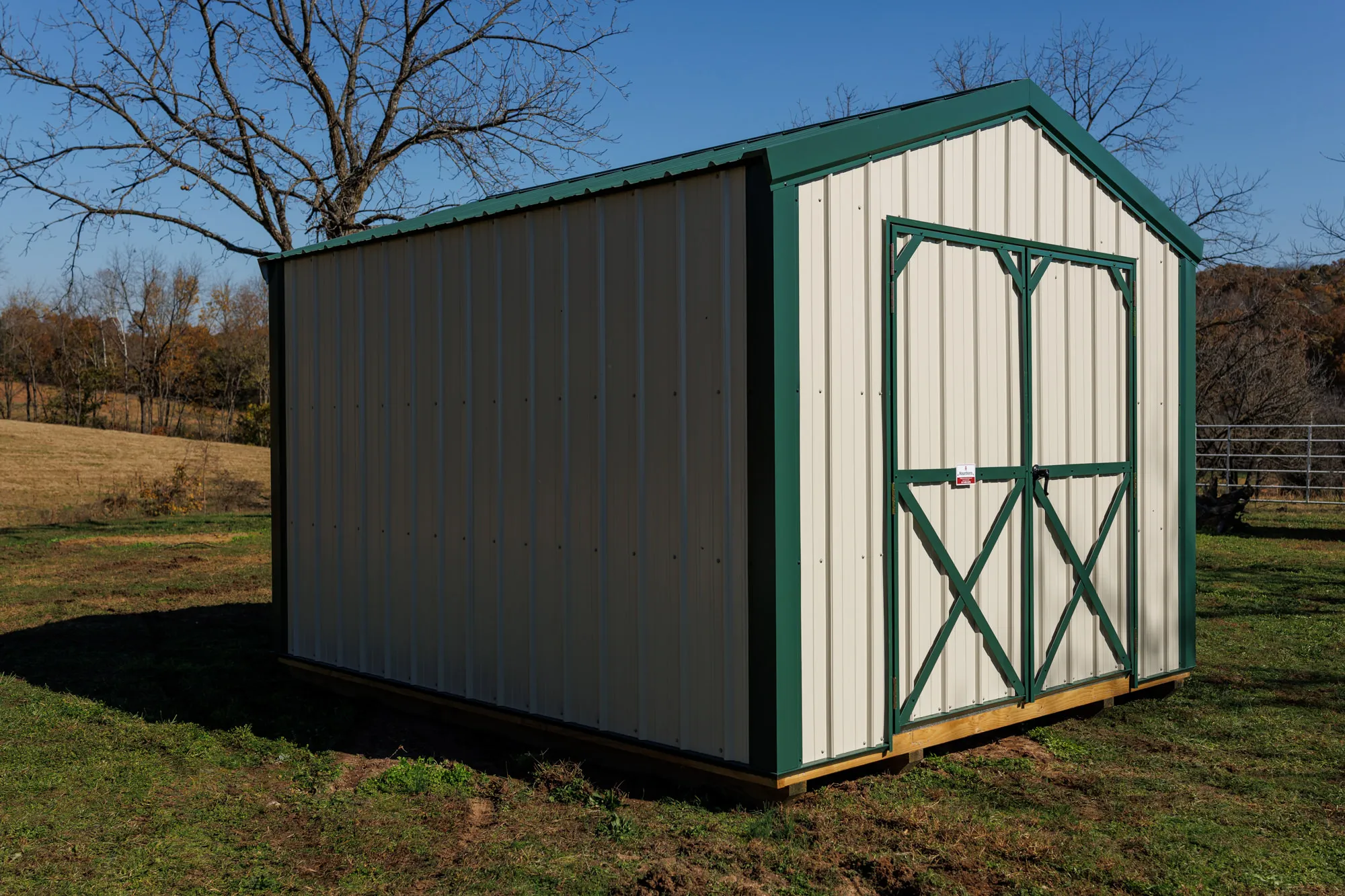 Cream metal shed with forest-green trim and X-braced double doors