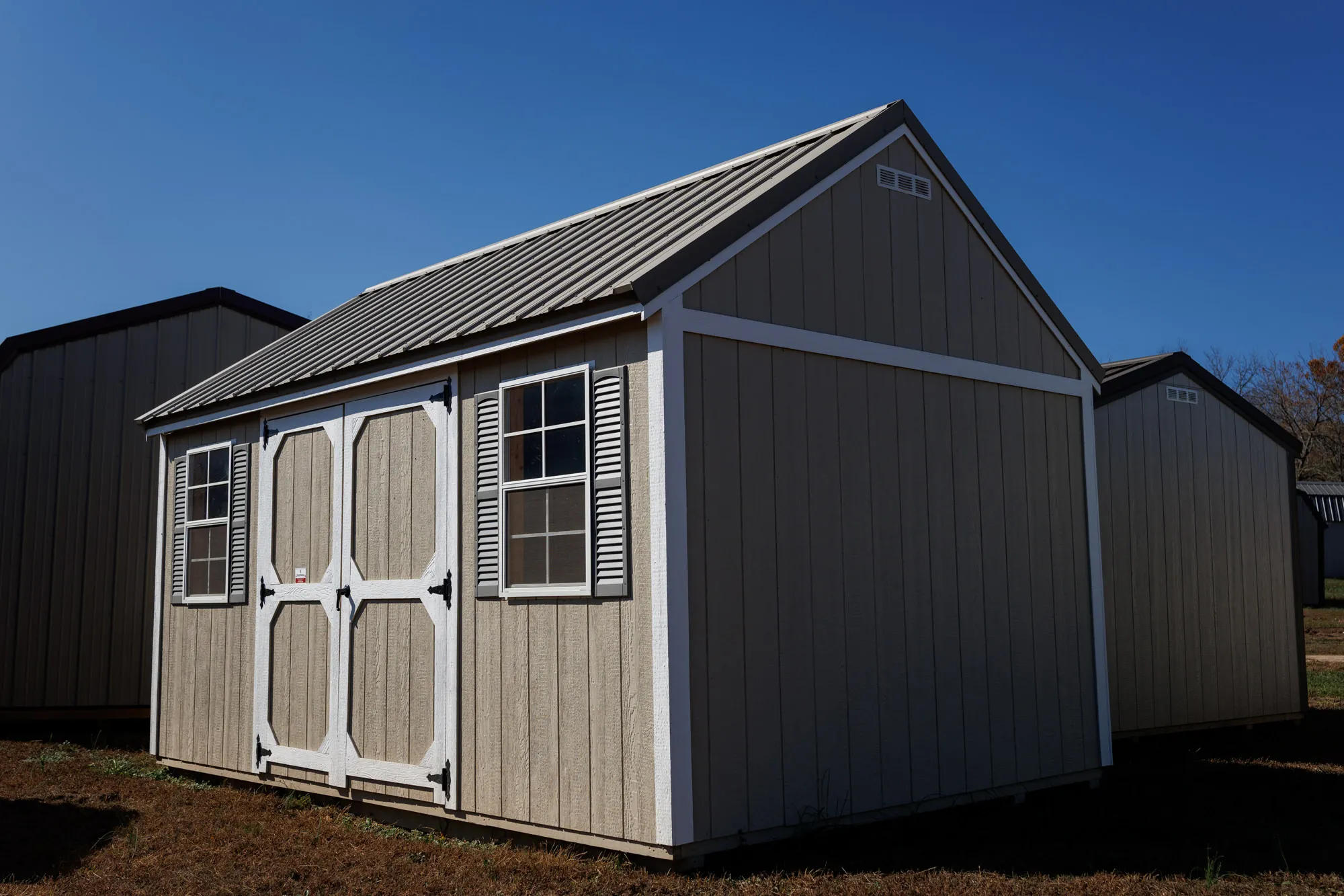 Gray lofted barn with a metal roof, shuttered windows and white trim
