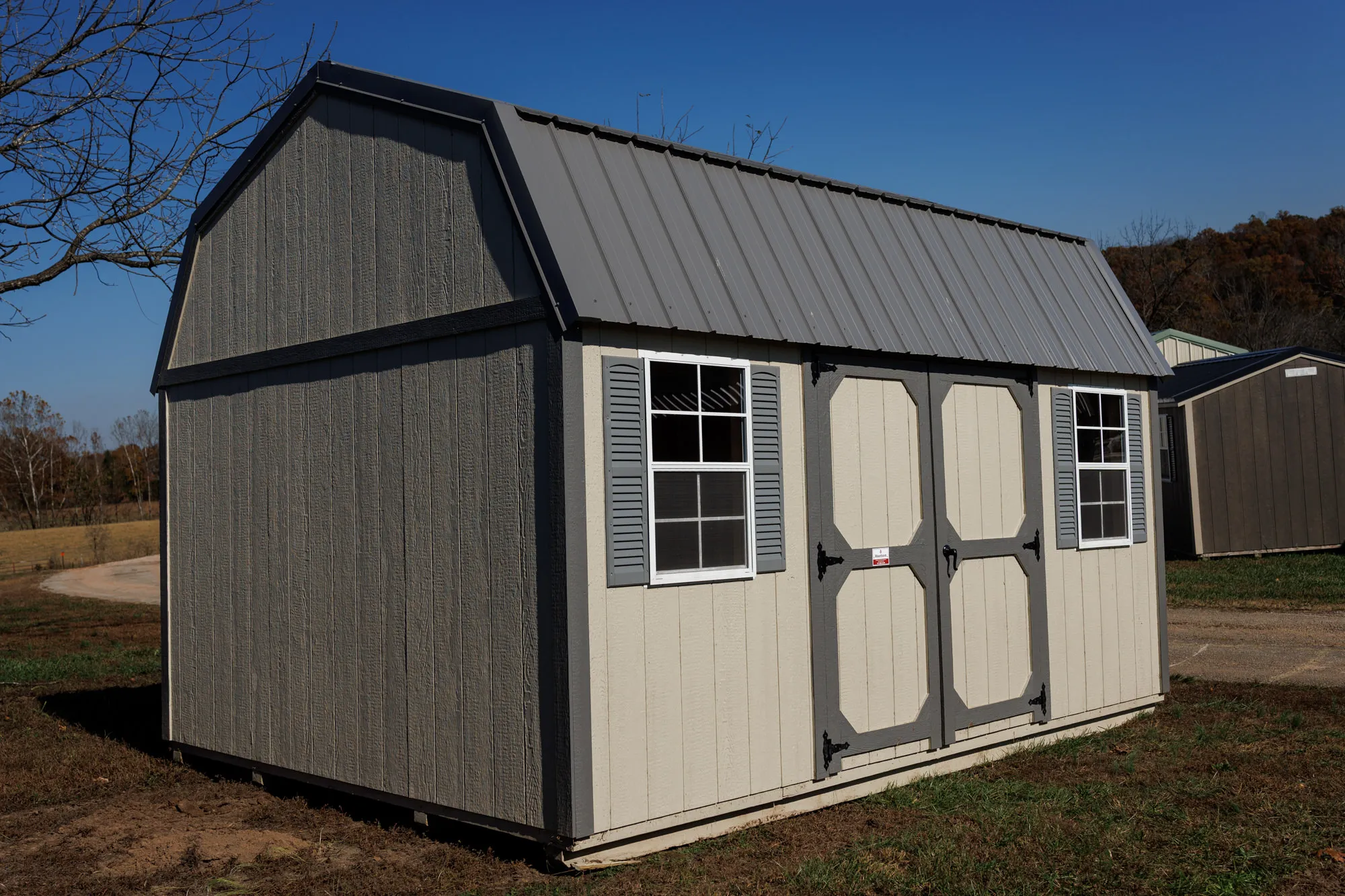 Gray gambrel lofted barn with white-trimmed windows and double doors