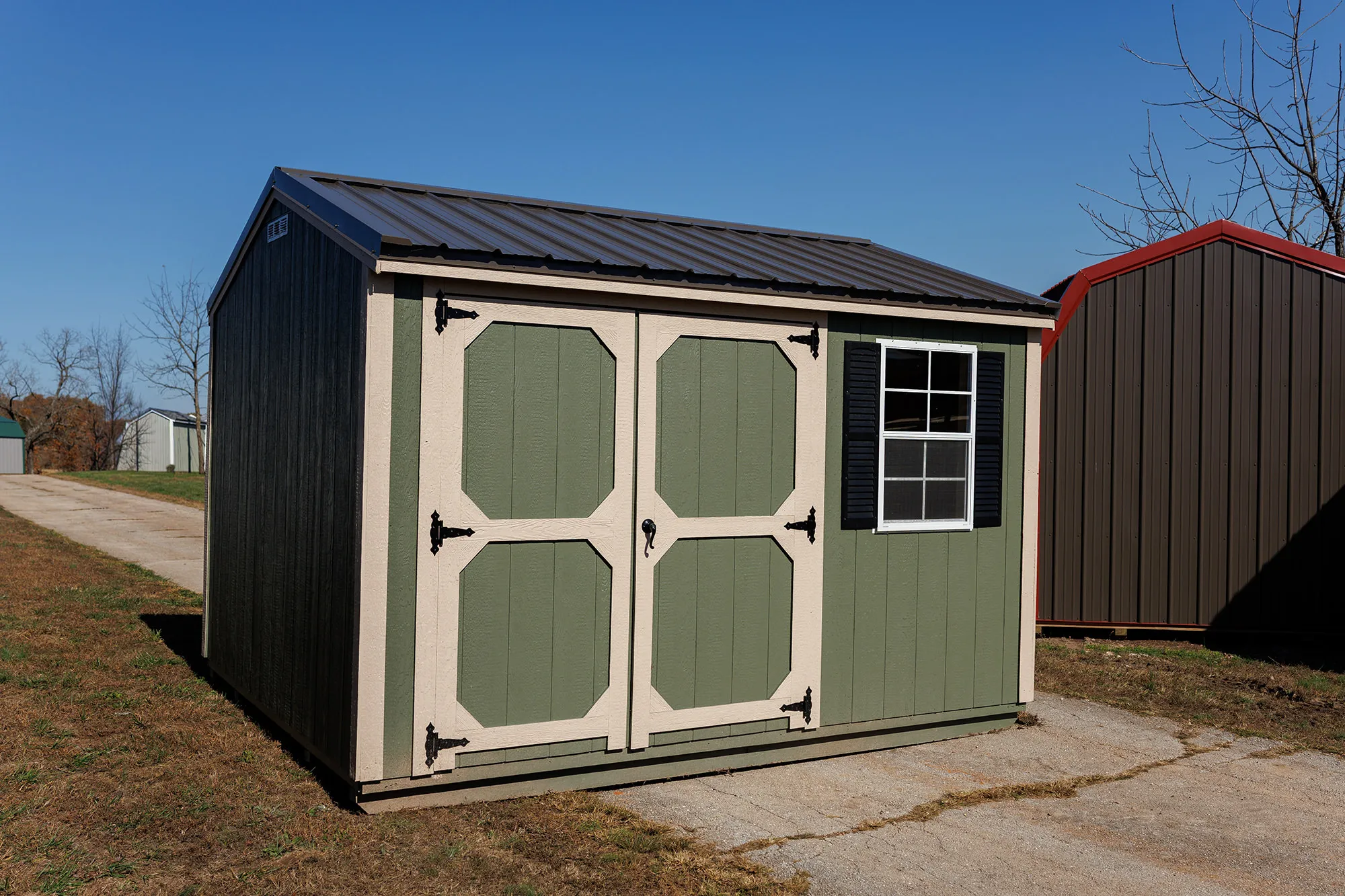 Sage-green shed with cream double doors and a black-shuttered window